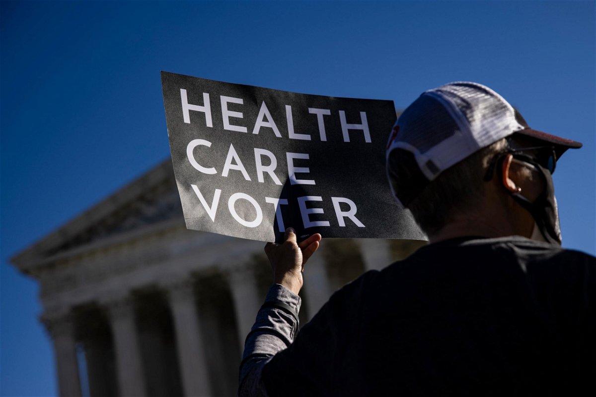 <i>Samuel Corum/Getty Images</i><br/>A supporter of the Affordable Care Act (ACA) stands in front of the Supreme Court of the United States in 2020.