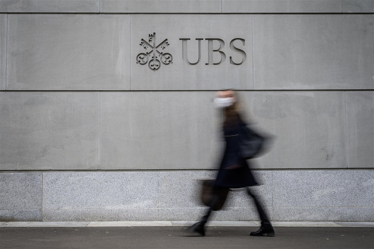 <i>Fabrice Coffrini/AFP/Getty Images</i><br/>A pedestrian wearing a facemask walks by the logo of Swiss banking giant UBS engraved on the wall of its headquarters in Zurich on March 3.