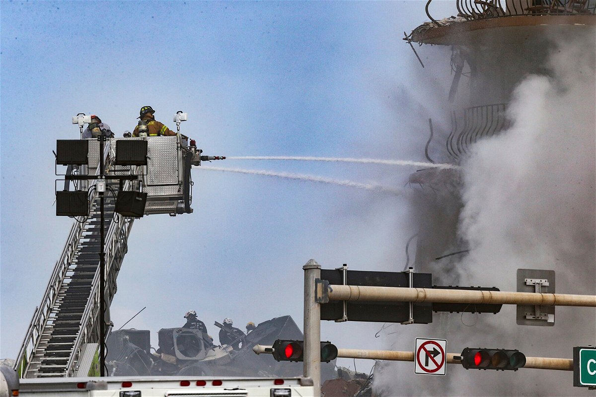 <i>Al Diaz/AP</i><br/>Firefighters battle a blaze as rescue workers search debris at the 12-story oceanfront condo