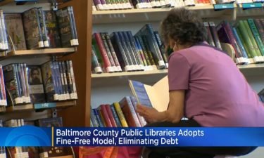 A woman browses for books at a library in the Baltimore County system. The system has adopted a fine-free model and eliminated outstanding balances.