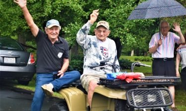 John Stanley Pioro (center) waves to participants in a car parade in celebration of his 100th birthday.