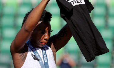 Gwen Berry holds up a shirt reading "Activist Athlete" as she celebrates finishing third in the Women's Hammer Throw final on day nine of the 2020 US Olympic Track & Field Team Trials on June 26
