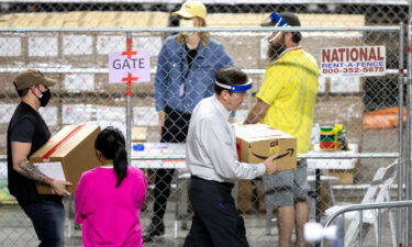 Former Arizona Secretary of State Ken Bennett (right) works to move ballots from the 2020 general election at Veterans Memorial Coliseum on May 1 in Phoenix
