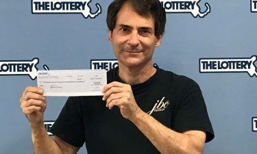 Stephen Toto displays his check after winning the Massachusetts lottery a second time.