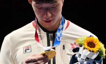 Fencing gold medallist Cheung Ka Long of Hong Kong looks at his medal while on the podium during the medal ceremony for the Men's Individual Foil during the Tokyo 2020 Olympic Games at the Makuhari Messe Hall in Chiba City