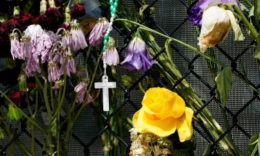 A cross hangs among wilting flowers at a makeshift memorial near the Champlain Towers South condo building.