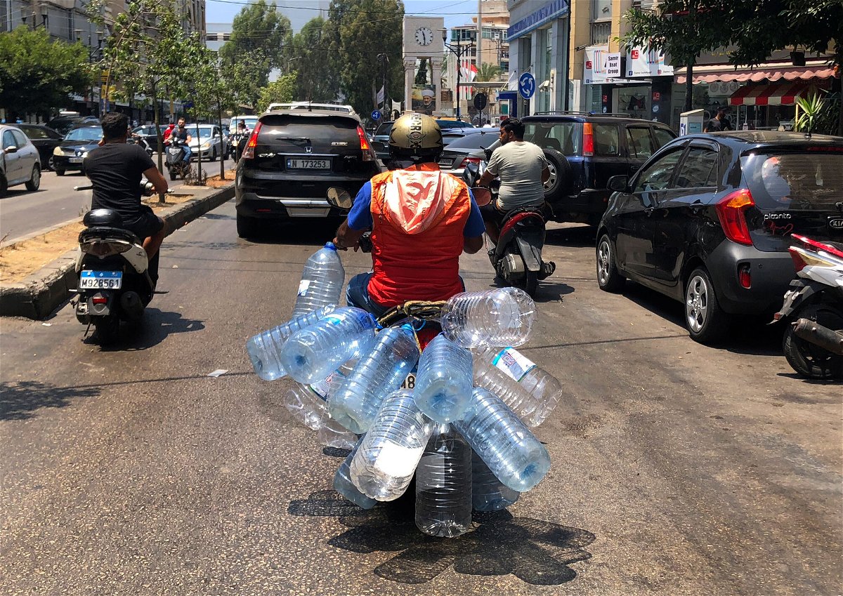 <i>Hussein Malla/AP</i><br/>A man rides his scooter with empty water bottles to fill them with gasoline
