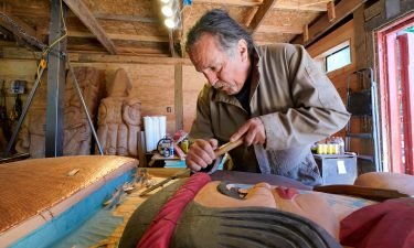 Lummi Nation lead carver Jewell James works on the final details of a nearly 25-foot totem pole to be gifted to the Biden administration at the end of July.