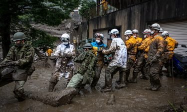 Rescue workers pull a rope to remove debris from a house damaged by a landslide on July 04 in Atami