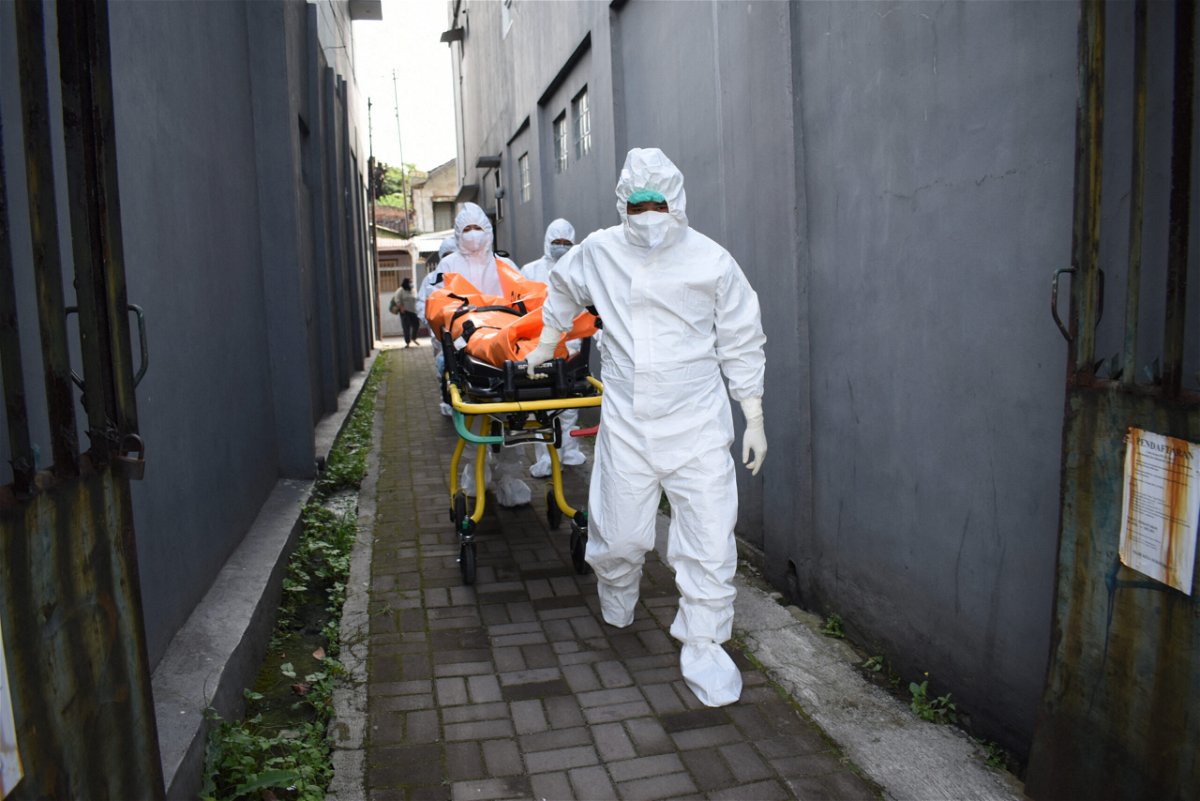 <i>TIMUR MATAHARI/AFP/AFP via Getty Images</i><br/>Health workers remove the body of a Covid-19 victim who died while isolating at home in Indonesia on July 14.