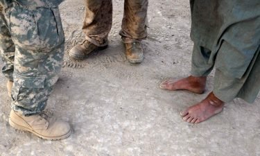 A U.S. Marine (C) talks through his interpreter (L) to an Afghan man during a patrol on July 6