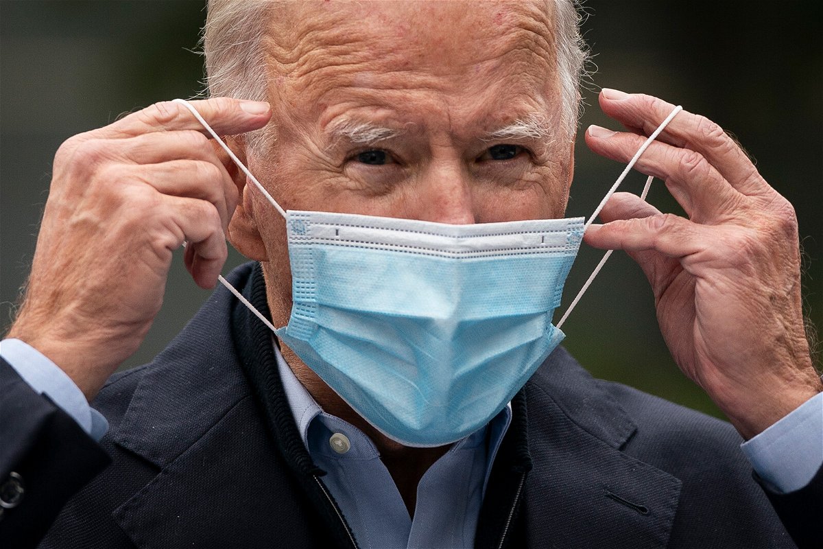 <i>Drew Angerer/Getty Images</i><br/>Then-Democratic presidential nominee Joe Biden puts on a face mask while speaking to reporters at a voter mobilization center on October 26