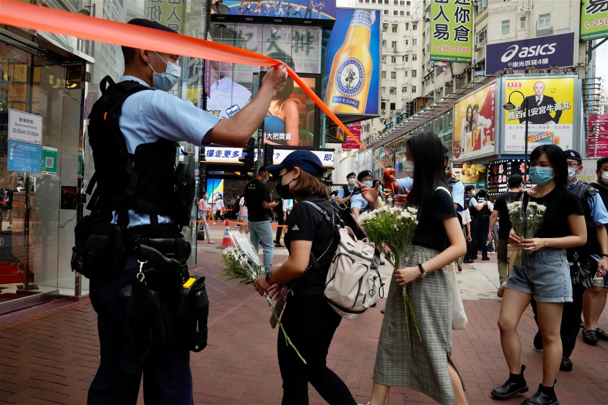 <i>Kin Cheung/AP</i><br/>People hold flowers to mourn the death of the assailant.