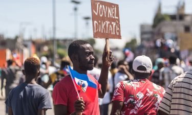 People hold up signs during a demonstration against the Moise government in Haiti's capital on February 14.