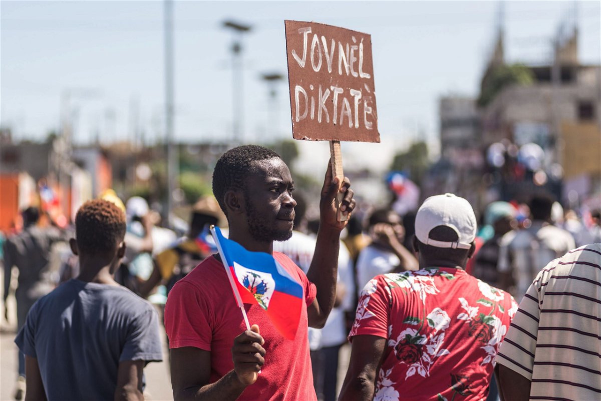 <i>Reginald Louissaint Jr./AFP/Getty Images</i><br/>People hold up signs during a demonstration against the Moise government in Haiti's capital on February 14.
