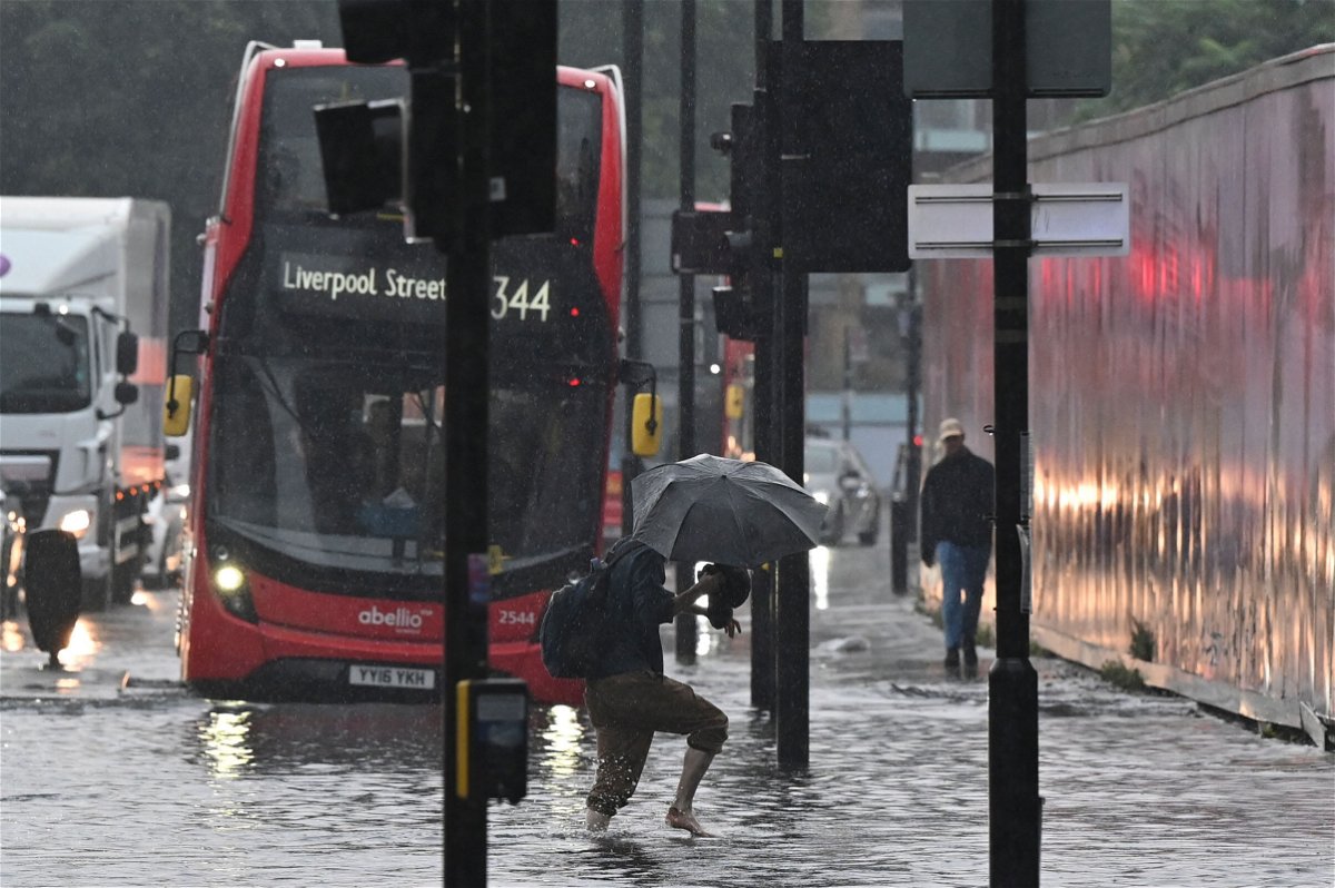 <i>JUSTIN TALLIS/AFP/Getty Images</i><br/>A pedestrian crosses through deep water on a flooded road in London on July 25. Climate and infrastructure experts have been warning for years that London