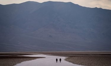 People walk on salt flats in Badwater Basin in Death Valley National Park