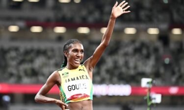 Jamaican runner Natoya Goule raises an arm after running the fastest time in the heat