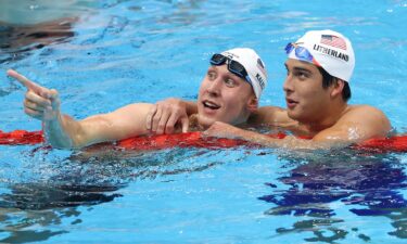 Two swimmers look on from a pool