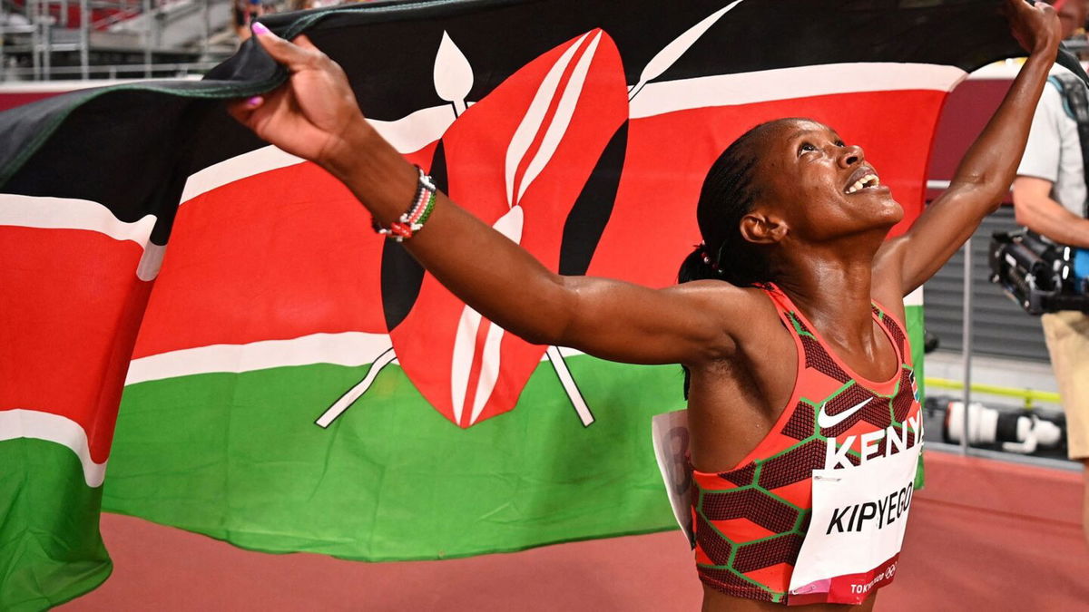 Kenya's Faith Kipyegon celebrates with her national flag after winning the gold medal in the women's 1500m final during the Tokyo 2020 Olympic Games