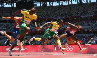 Jamaica's Hansle Parchment (L) crosses the finish line to win ahead of second-placed USA's Grant Holloway (R) and third-placed Jamaica's Ronald Levy (C) in the men's 110m hurdles final during the Tokyo 2020 Olympic Games