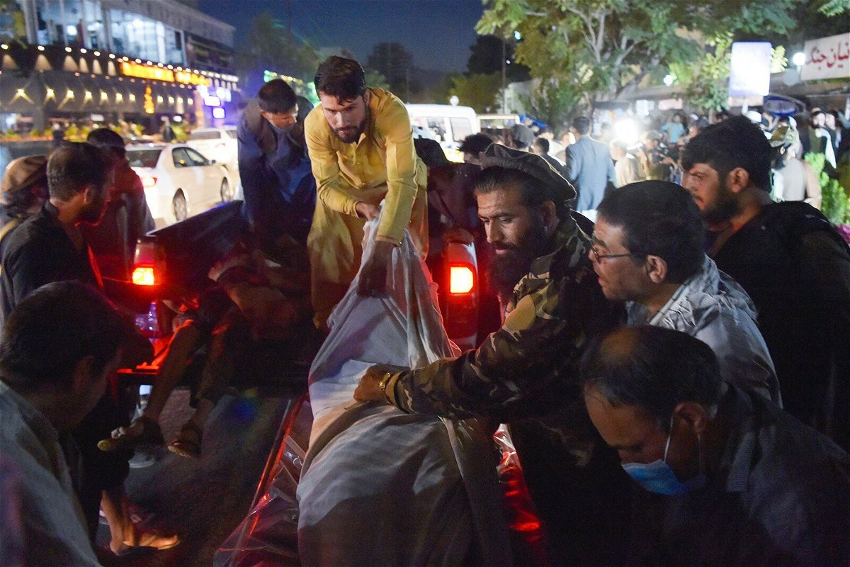 <i>Wakil Kohsar/AFP/Getty</i><br/>Volunteers and medical staff unload bodies from a pickup truck outside a hospital after two powerful explosions outside the airport in Kabul on August 26.