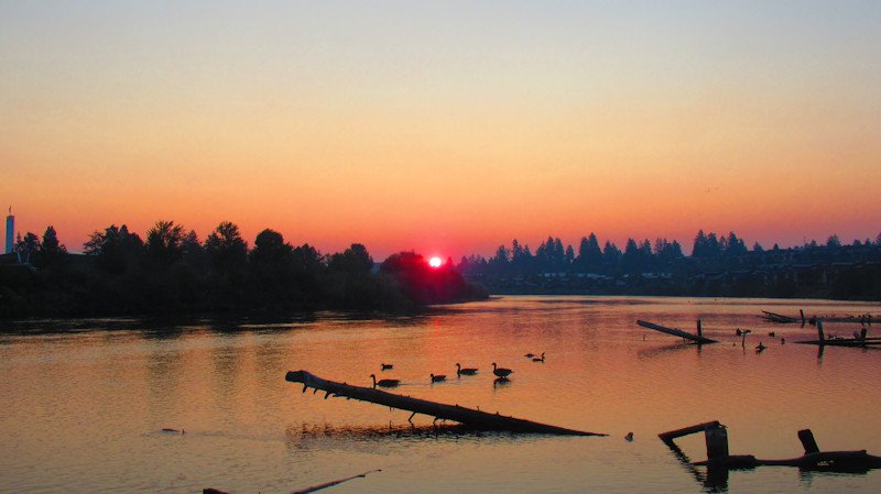 A red sun rises over the Deschutes River in Bend on Sunday morning amid smoke and haze