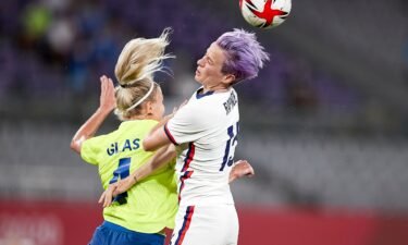 Purple-haired Megan Rapinoe goes up for a header against Sweden's Hanna Glas