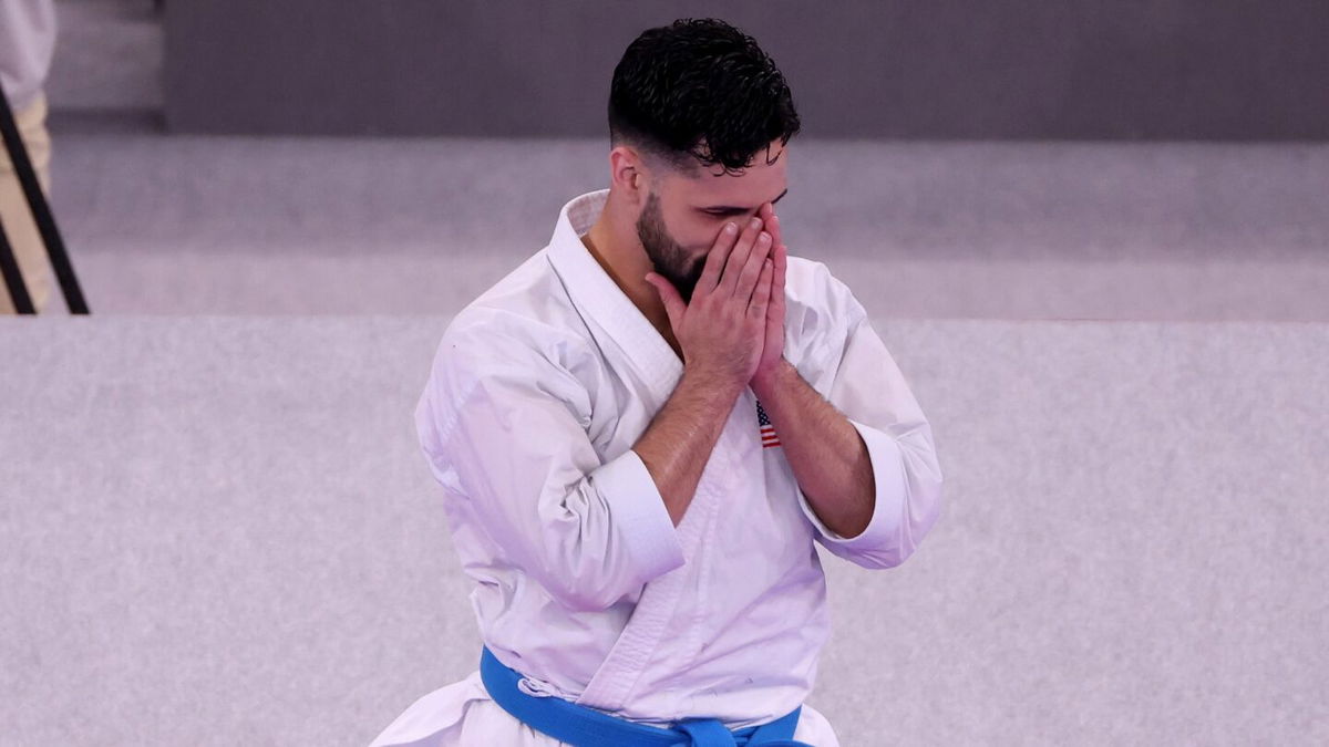 An emotional Ariel Torres folds his hands in front of face after winning bronze in men's kata