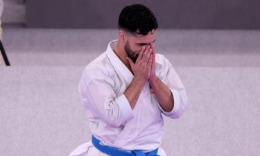 An emotional Ariel Torres folds his hands in front of face after winning bronze in men's kata