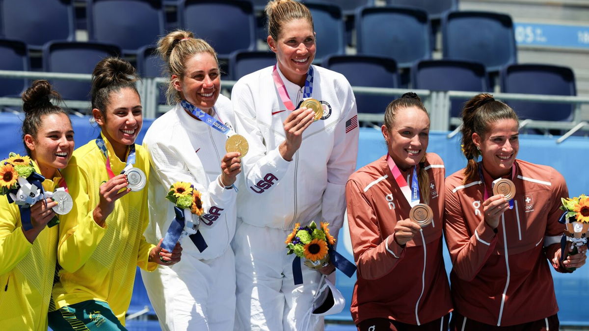 Women's beach volleyball's six medal winners smile and show their prizes