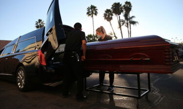 Embalmer and funeral director Kristy Oliver (R) and funeral attendant Sam Deras load the casket of a person who died after contracting COVID-19 into a hearse at East County Mortuary on January 15