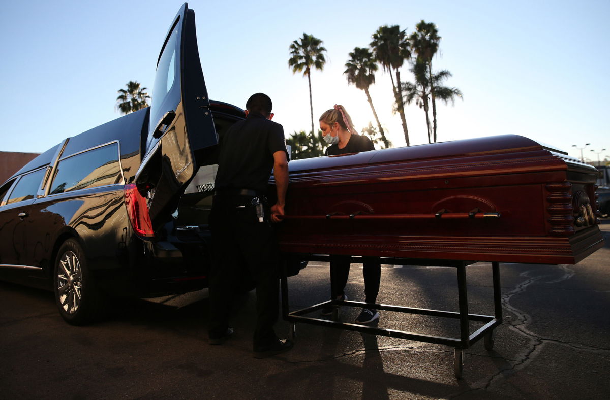 <i>Mario Tama/Getty Images</i><br/>Embalmer and funeral director Kristy Oliver (R) and funeral attendant Sam Deras load the casket of a person who died after contracting COVID-19 into a hearse at East County Mortuary on January 15