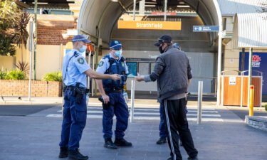 Police officers approach a man for not wearing a mask at Strathfield station
