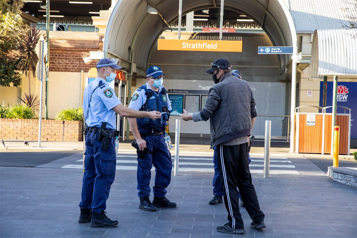 <i>Jenny Evans/Getty Images</i><br/>Police officers approach a man for not wearing a mask at Strathfield station