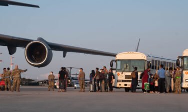 A group of Afghan evacuees depart a C-17 Globemaster III aircraft at Ramstein Air Base