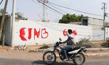 A motorist passes by a wall with a graffiti of the Jalisco New Generation Cartel (CJNG) in Michoacan state
