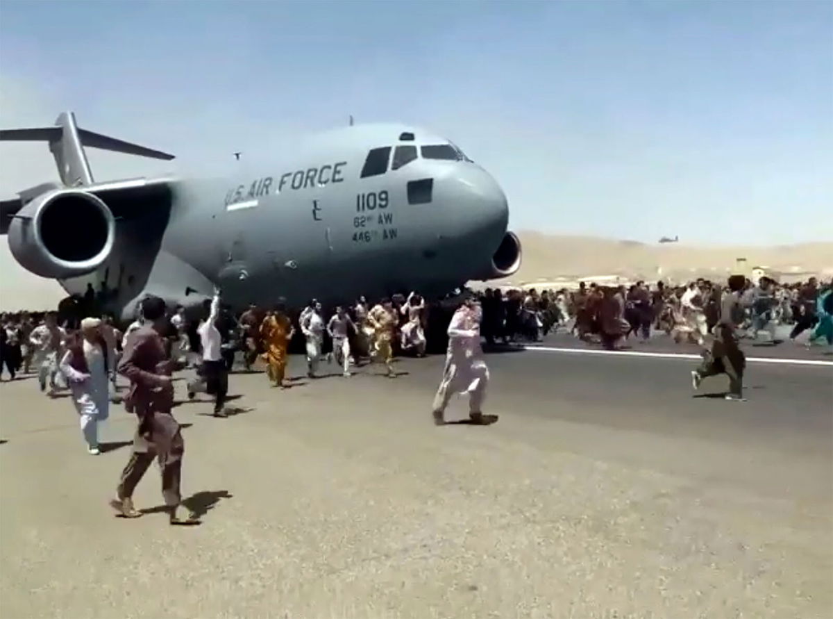 <i>Verified UGC/AP</i><br/>Hundreds of people run alongside a U.S. Air Force C-17 transport plane as it moves down a runway of the international airport
