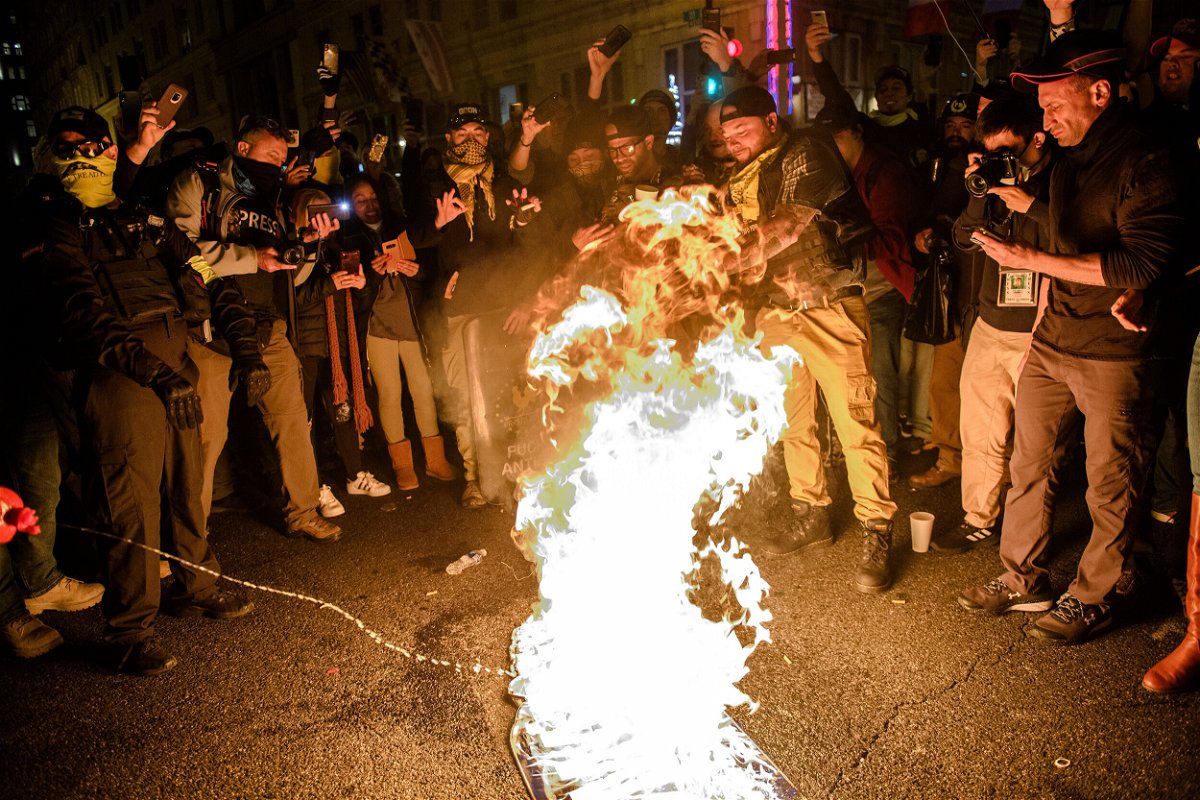 <i>Amy Harris/Shutterstock/.FILE</i><br/>A Proud Boy adds fuel to a Black Lives Matter flag on fire as leader Enrique Tarrio and other members gather in the streets following the 'Million MAGA March' on December 12