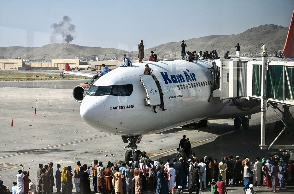 <i>Wakil Kohsar/AFP/Getty Images</i><br/>Afghan people climb atop a plane attempt to leave Kabul on Aug. 16. The US has come under scrutiny over its hasty and chaotic withdrawal