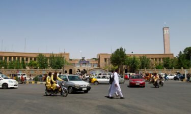 Pedestrians and motorists travel near the Herat provincial official office on Aug. 14 after the province was taken by the Taliban several days before.