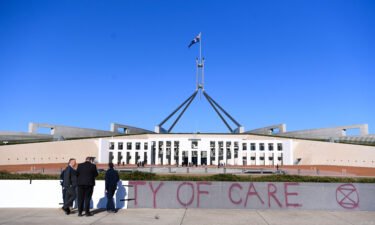 Workers cover the slogan 'Duty of Care' after an Extinction Rebellion protest outside Parliament House