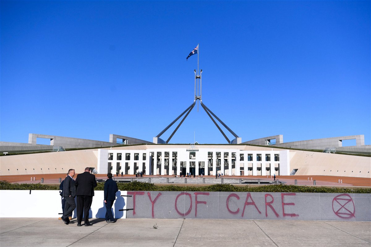 <i>Lukas Coch/AAP Image/Reuters</i><br/>Workers cover the slogan 'Duty of Care' after an Extinction Rebellion protest outside Parliament House