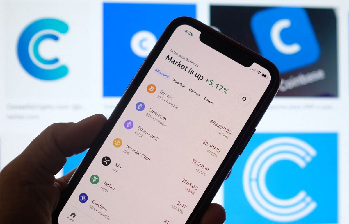 <i>CHRIS DELMAS/AFP/AFP via Getty Images</i><br/>This illustration photo shows the Coinbase logo in the background as a person checks cryptocurrencies prizes on a smartphone in Los Angeles on April 13. Members of the cryptocurrency world are donating to crypto-focused organizations