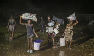 People affected by the earthquake walk under the rain of Tropical Depression Grace at a refugee camp in Les Cayes