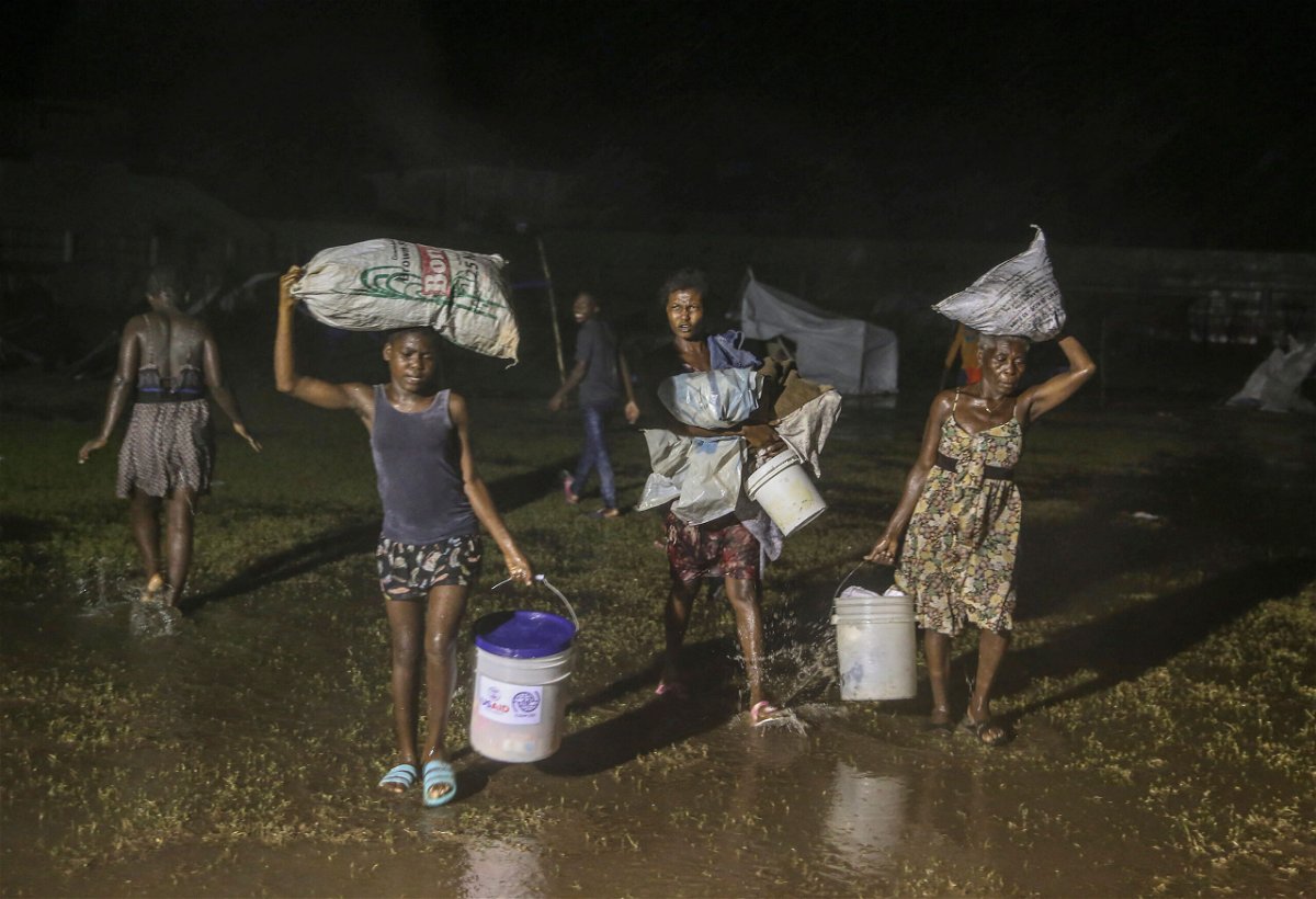 <i>Joseph Odelyn/AP</i><br/>People affected by the earthquake walk under the rain of Tropical Depression Grace at a refugee camp in Les Cayes