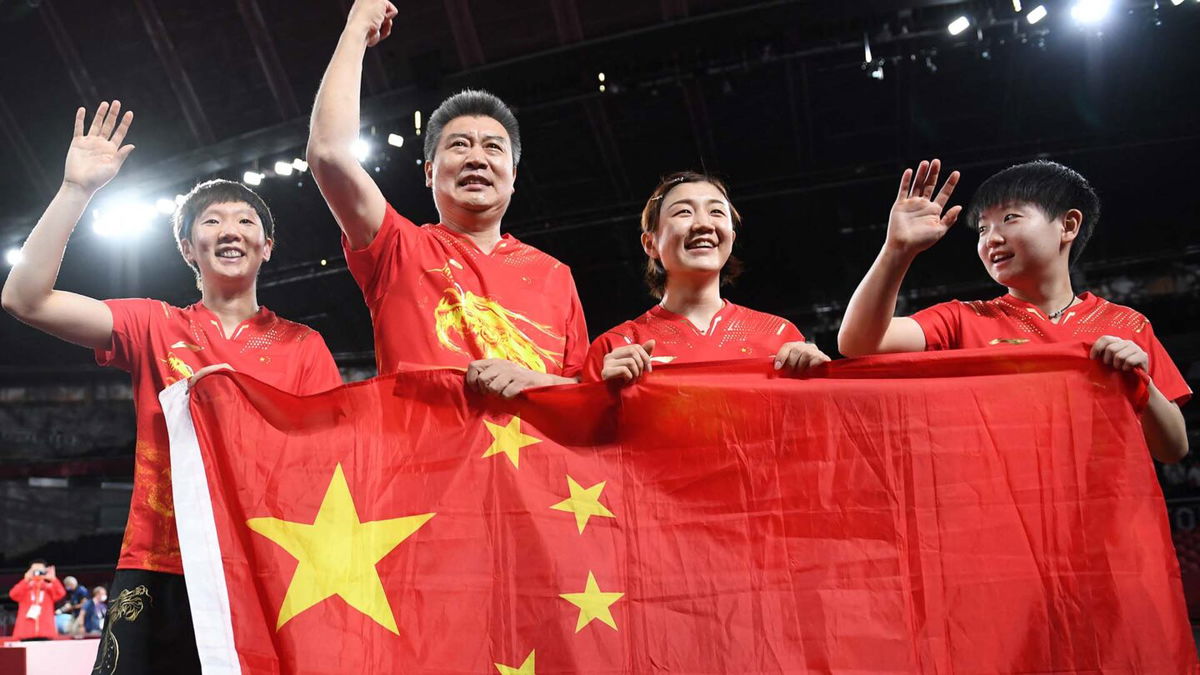 The Chinese Women's Table Tennis Team celebrates with their flag after their gold medal win