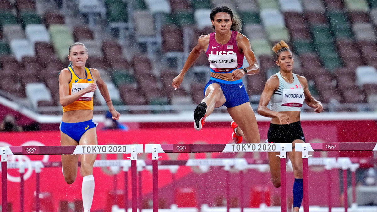 Sydney McLaughlin jumps over a hurdle in the rain