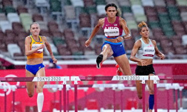 Sydney McLaughlin jumps over a hurdle in the rain