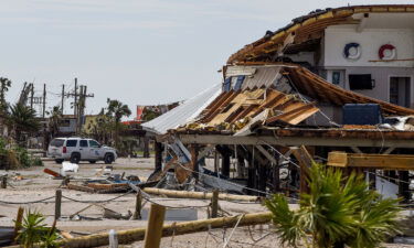 A Louisiana State Trooper keeps watch over damaged homes on Grand Isle on Tuesday.